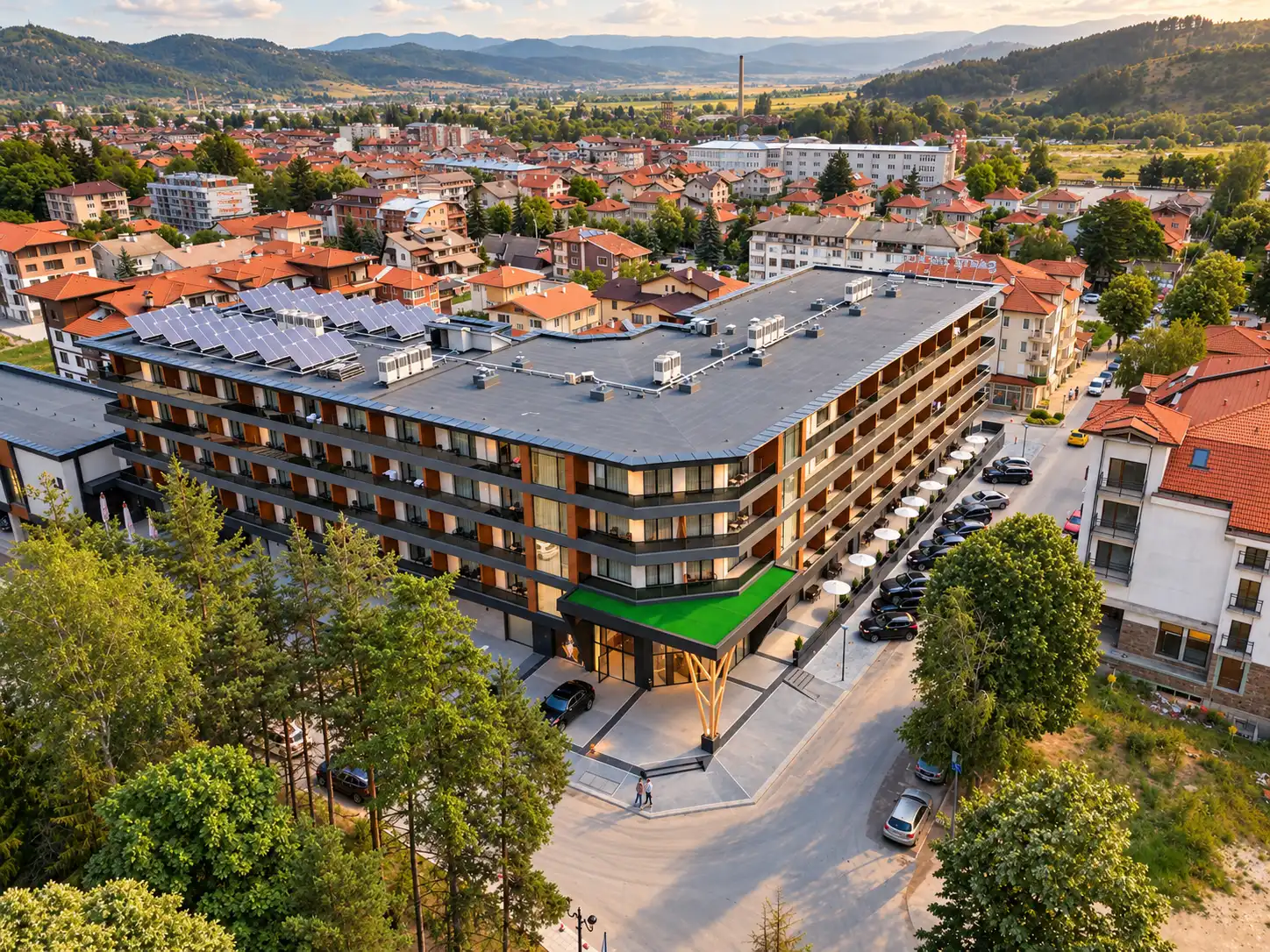Santé SPA Hotel във Велинград, заснет с дрон: модерна сграда със соларни панели, главен вход и Родопите зад нея