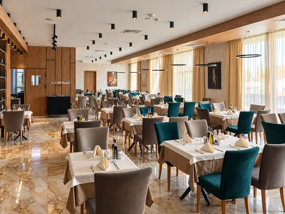 Основната зала на ресторанта в Santé SPA Hotel, Велинград: сервирани маси, тюркоазени столове и мраморен под
