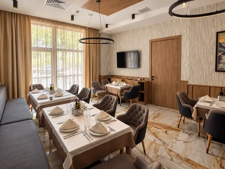 Малката зала на ресторанта в Santé SPA Hotel, Велинград: тапицирани кресла, сервирани маси и мраморен под